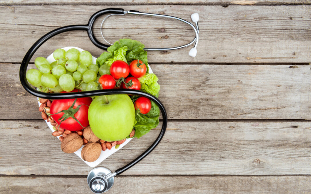 A heart shaped plate stacked with healthy foods and a stethoscope representing the need for a healthy diet after hiatal hernia surgery.