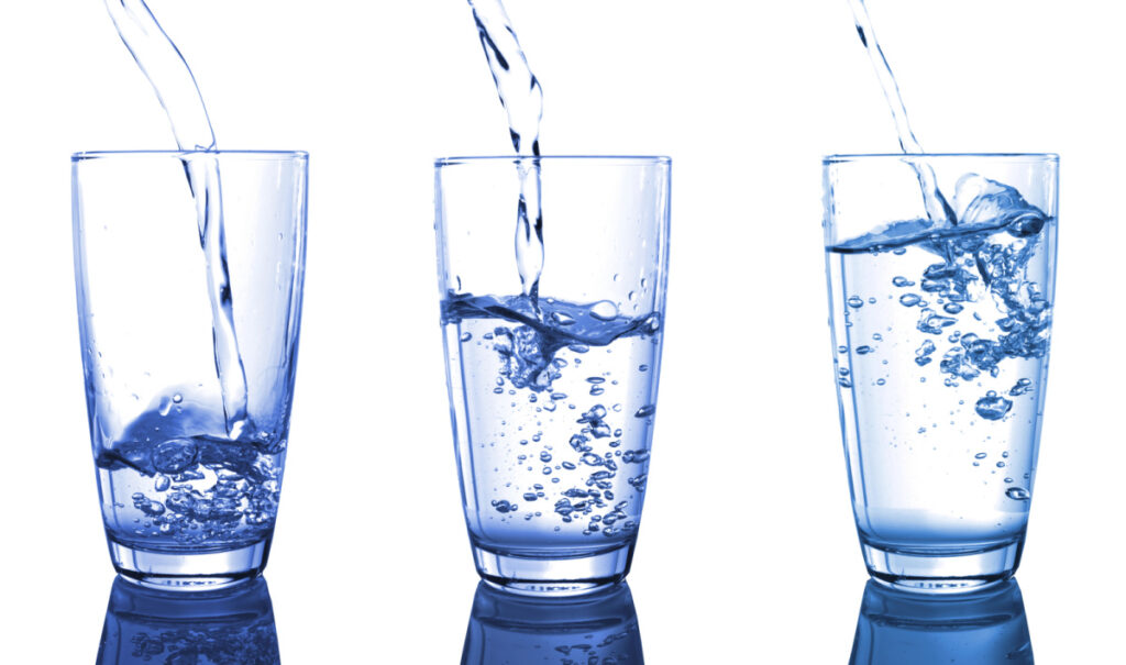 3 glasses of water at varying levels of fullness, symbolizing hydration as an important aspect of a patient’s diet after hiatal hernia surgery. 