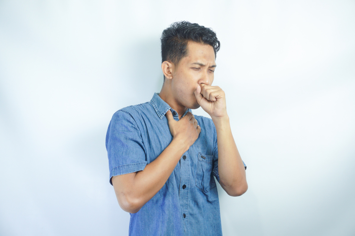 A young man in the act of coughing, wondering if acid reflux can cause coughing.