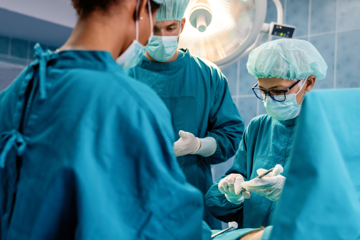 A team of doctor’s in scrubs and caps preparing to do a no mesh hernia surgery.